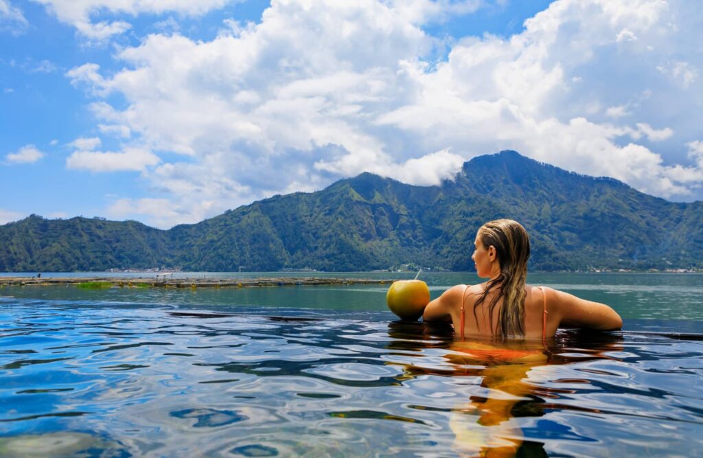 Relax in infinity pool with lake view. Natural hot spring spa under Batur volcano.