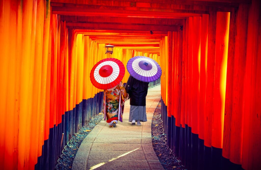 Couple in traditional japanese kimonos walking at Fushimi Inari Shrine in Kyoto, Japan.